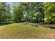A large backyard features a lush green lawn, a playground, and mature trees, offering plenty of space for outdoor enjoyment at 619 Archibald Rd, Concord, NC 28025