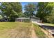 Quaint home featuring a well-manicured lawn, green exterior, attached garage, and a long driveway, nestled among mature trees at 619 Archibald Rd, Concord, NC 28025
