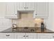 Close-up of kitchen countertop with range, tile backsplash, and sleek white cabinets at 7923 Mountain Shore Dr, Sherrills Ford, NC 28673