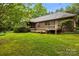 Brick home's lovely green backyard showcases a spacious wood deck, green grass, and tree coverage at 8368 Fairfield Forest Rd, Denver, NC 28037