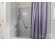 Full bathtub with gray walls, with a shower head and curtain, a bright interior, and a window at 8368 Fairfield Forest Rd, Denver, NC 28037