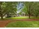 Beautiful brick home featuring a well-manicured lawn and mature trees providing shade at 8368 Fairfield Forest Rd, Denver, NC 28037