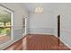 Formal living room with hardwood floors, large windows, decorative chandelier, and warm walls at 8368 Fairfield Forest Rd, Denver, NC 28037