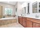 A luxurious bathroom with a soaking tub, a double vanity, and a window at 9930 Karras Commons Way, Matthews, NC 28105
