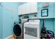 Bright laundry room with washer, dryer, white cabinets, and shelving at 9930 Karras Commons Way, Matthews, NC 28105