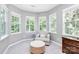 Bright sitting room with an armchair and ottoman in front of three windows at 9930 Karras Commons Way, Matthews, NC 28105