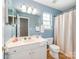 This bathroom features a sink, toilet, shower curtain, and white cabinets at 10408 Milstead Ct, Charlotte, NC 28215