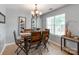 Cozy dining room featuring a wooden table, chandelier, and a large window with blinds at 10408 Milstead Ct, Charlotte, NC 28215