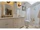 Bright bathroom featuring double vanity, a tub with shower, and wainscoting detail at 12028 Royal Lytham Ct, Charlotte, NC 28277
