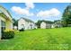 Large, grassy backyard showcasing the rear of several homes in a suburban neighborhood under a sunny sky at 12803 Matisse Ln, Charlotte, NC 28215