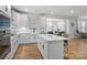 Bright, open kitchen featuring white cabinets, wood floors, and modern appliances with an island and barstool seating at 1287 Fishing Creek Rd, Lake Wylie, SC 29710