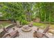 Landscaped backyard with stone fire pit area, surrounded by mature trees at 13312 Edgetree Dr, Pineville, NC 28134