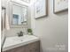 Modern half bathroom featuring a floating vanity, a framed mirror, sleek fixtures, and tasteful floral decor at 13312 Edgetree Dr, Pineville, NC 28134