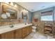 Large bathroom with double sinks, wooden cabinets, and a window at 13312 Edgetree Dr, Pineville, NC 28134