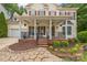 Inviting front porch with decorative columns, fan, seating, and charming landscaping at 13312 Edgetree Dr, Pineville, NC 28134