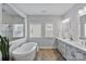 Elegant bathroom featuring a freestanding tub, herringbone floor, and double vanity with modern fixtures, offering comfort at 14218 Morningate St, Huntersville, NC 28078