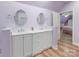 Stylish bathroom featuring a dual vanity, oval mirrors, white cabinets, and light-purple walls at 17112 Green Dolphin Ln, Cornelius, NC 28031