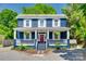 Charming two-story home featuring a inviting front porch, complemented by a vibrant red door and lush landscaping at 309 N Congress N St, York, SC 29745