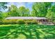 Expansive backyard featuring a well-maintained lawn, mature trees, patio, and charming brick ranch-style home at 3810 Springway Dr, Gastonia, NC 28056