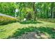 A well-manicured backyard features lush green grass, mature trees, a wooden fence and a storage shed at 3810 Springway Dr, Gastonia, NC 28056