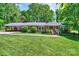 Charming brick ranch home with lush lawn, carport, and inviting front porch nestled among mature trees at 3810 Springway Dr, Gastonia, NC 28056