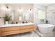 Elegant bathroom highlighting a double vanity, arched mirrors, modern lighting and a freestanding tub with marble accents at 4907 Ardenwoods Dr, Charlotte, NC 28215