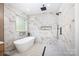 Modern bathroom showcasing white marble walls, a freestanding tub, matte black fixtures, and a rain shower head at 4907 Ardenwoods Dr, Charlotte, NC 28215