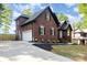 Brick home featuring a side-entry garage, lush landscaping, and a classic architectural design at 4907 Ardenwoods Dr, Charlotte, NC 28215