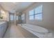 Luxurious bathroom featuring a soaking tub, tiled floors, and large windows for natural light at 5250 Meadowcroft Way, Fort Mill, SC 29708