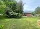 Expansive backyard featuring lush green grass, mature trees, and a brick home exterior at 601 Scottsbrook Dr, Charlotte, NC 28213