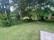 Lush backyard with mature trees and lawn offering a serene outdoor space and a small storage building at 601 Scottsbrook Dr, Charlotte, NC 28213