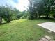 Large backyard with a lush lawn and mature trees, offering a tranquil outdoor space and partial slab of concrete at 601 Scottsbrook Dr, Charlotte, NC 28213