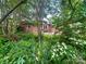 Backyard featuring lush greenery, flowers, brick home exterior with a concrete patio at 601 Scottsbrook Dr, Charlotte, NC 28213
