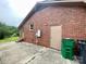 Exterior view of brick home with a concrete patio, showing side entry doors, and landscaping at 601 Scottsbrook Dr, Charlotte, NC 28213
