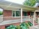 Inviting front porch with white railing, brick accents, and green front door at 601 Scottsbrook Dr, Charlotte, NC 28213