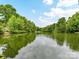 Scenic view of a tranquil lake surrounded by lush greenery, reflecting a clear blue sky with scattered clouds at 6017 Lake Providence Ln, Charlotte, NC 28277