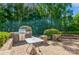 Outdoor patio with a built-in grill, stone benches, and lush greenery at 7128 Rock Bass Ct, Concord, NC 28025