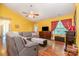 Bright living room with yellow walls, a grey couch, a TV, and wood floors at 814 Independence Dr, Wingate, NC 28174