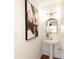 Stylish powder room boasts a pedestal sink, gold fixtures, and a modern black and white art piece at 8233 Christmas Ct, Charlotte, NC 28216