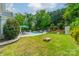 Spacious backyard with a pool, lush lawn, mature trees, and patio area, perfect for outdoor activities and relaxation at 8707 Darcy Hopkins Dr, Charlotte, NC 28277