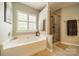 Bright bathroom featuring a soaking tub under a window and glass shower with neutral tile at 8707 Darcy Hopkins Dr, Charlotte, NC 28277
