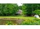 Picturesque backyard featuring a lush lawn, mature trees, tranquil pond, and charming wooden bridge at 9013 Yellow Pine Ct, Waxhaw, NC 28173