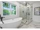 Contemporary bathroom features a freestanding tub, glass-enclosed shower, and large window with a view at 910 Everett Pl, Charlotte, NC 28205
