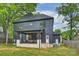 View of the home's backyard with covered porch, dark siding, and lush greenery at 910 Everett Pl, Charlotte, NC 28205