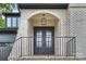 Charming front entrance with an arched brick porch, black wrought iron railings, and double glass doors at 910 Everett Pl, Charlotte, NC 28205