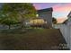 A serene backyard with a screened porch, a fenced yard, and lush lawn space under a colorful sky at 13502 Brandon Trail Dr, Charlotte, NC 28213