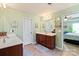 Bright bathroom with double sinks, cherry cabinets, and tile floors with a view to the bedroom at 13502 Brandon Trail Dr, Charlotte, NC 28213