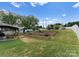 Landscaped backyard with brick retaining wall, colorful flowers, and a covered seating area at 137 Sugar Magnolia Dr, Mooresville, NC 28115