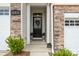 Charming front entryway with a black door, decorative wreath, stone accents, and manicured greenery at 15622 Little Bluestem St, Charlotte, NC 28278
