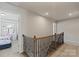 Upstairs hallway featuring carpet, wood banister, and view into bedroom at 15622 Little Bluestem St, Charlotte, NC 28278